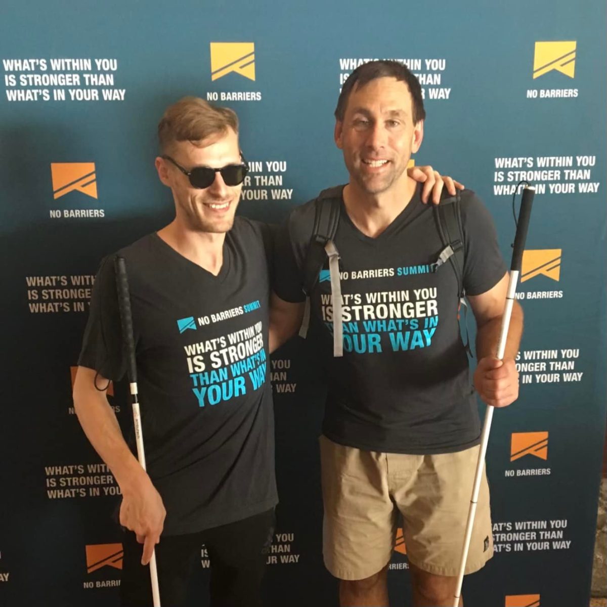 Erik and Casey at the 2017 No Barriers Summit holding canes and wearing No Barriers shirts.