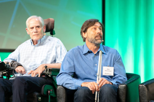Erik speaking on stage with Claude on his right and Aimee on his left.