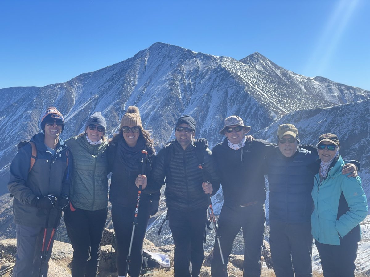 Erik and six (6) iCIMS team members taking a photo with the mountains rising above in the background.