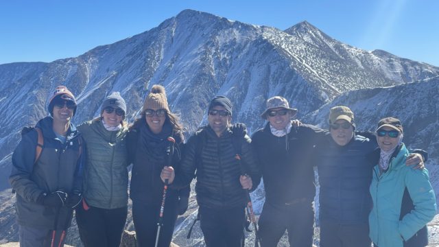 Erik and six (6) iCIMS team members taking a photo with the mountains rising above in the background.