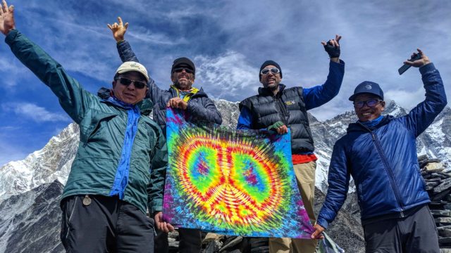 Erik, Timmy O'Neill and two Sherpas hold a tie-dye peace flag at a stop point climbing Ama Dablam in Nepal's Himalayan Range.